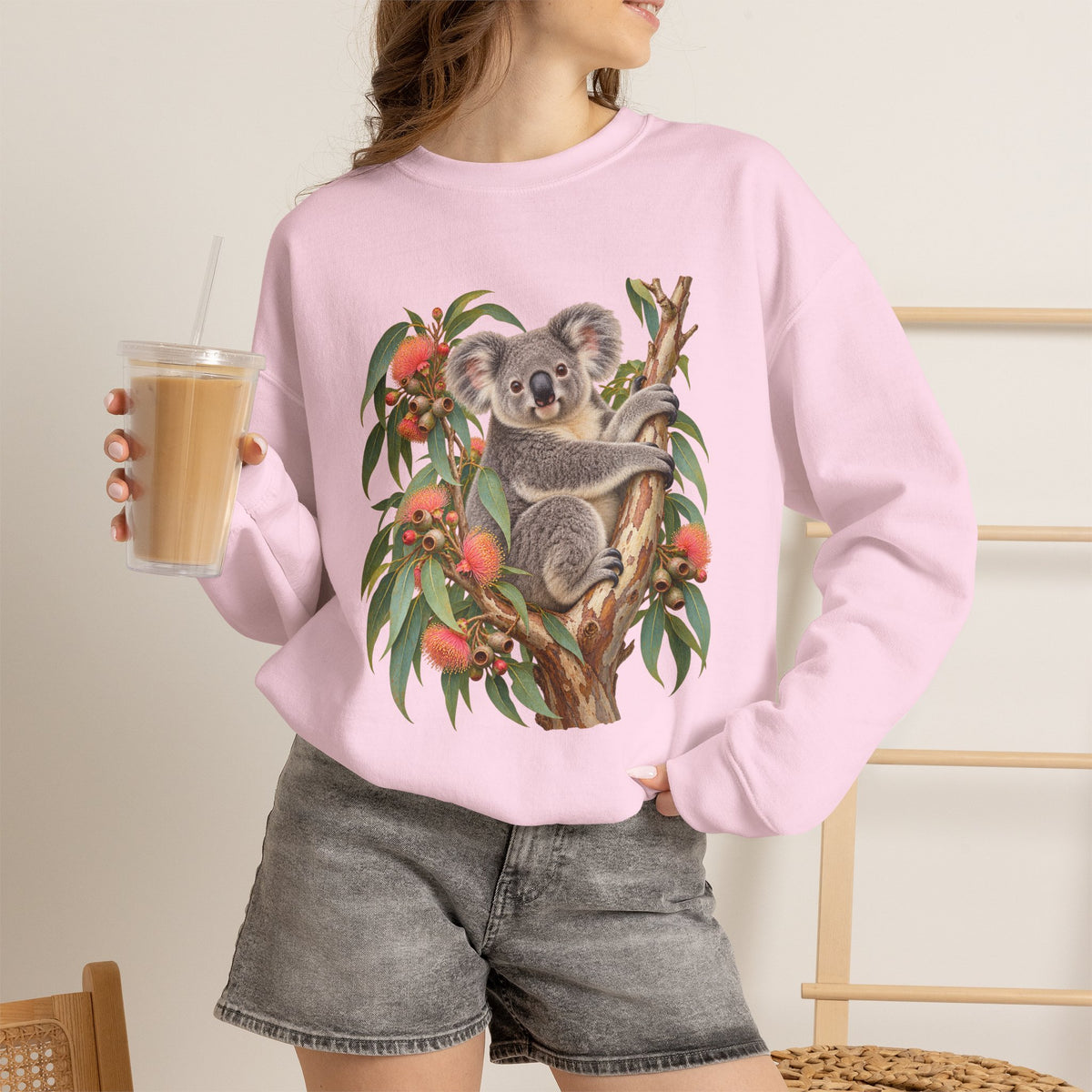 Booked for the Afternoon sweatshirt — a grey koala resting among eucalyptus leaves and coral-pink blossoms, on a unisex crewneck