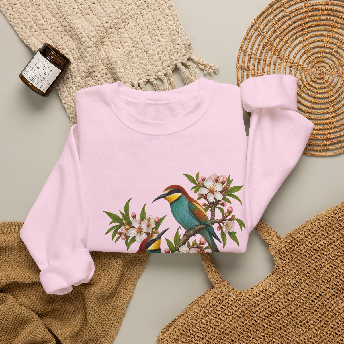 The Scenic Way Home sweatshirt — two birds with teal, golden-yellow and rust plumage perched among cream and blush blossoms, on a unisex crewneck