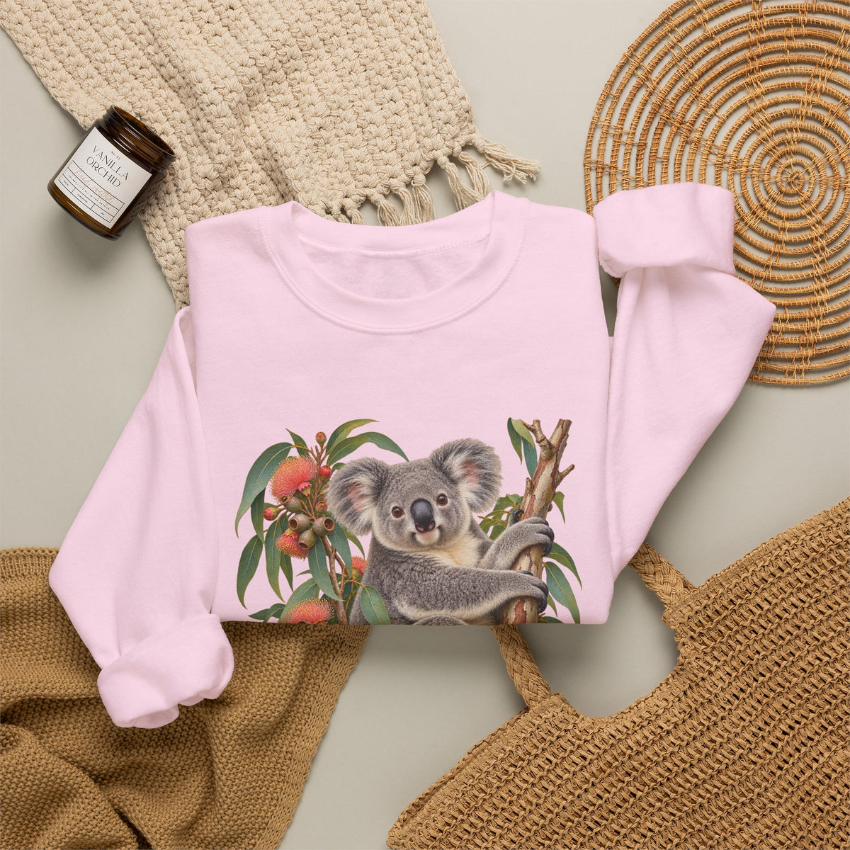 Booked for the Afternoon sweatshirt — a grey koala resting among eucalyptus leaves and coral-pink blossoms, on a unisex crewneck