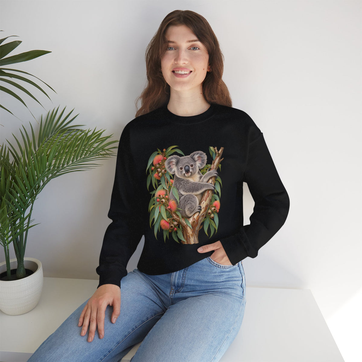 Booked for the Afternoon sweatshirt — a grey koala resting among eucalyptus leaves and coral-pink blossoms, on a unisex crewneck