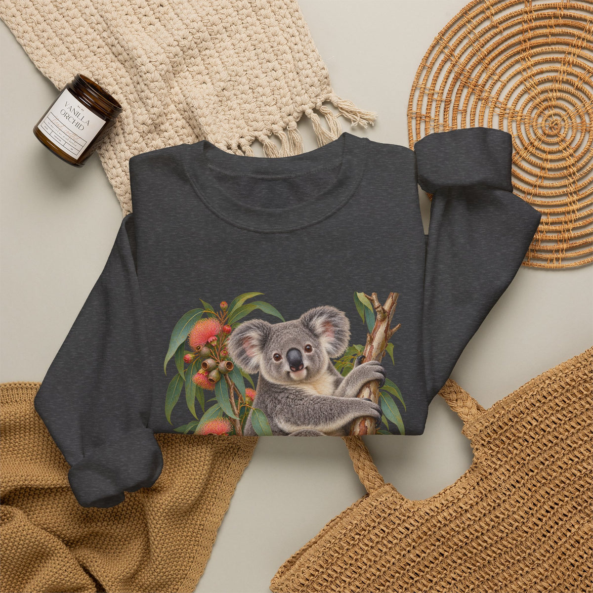 Booked for the Afternoon sweatshirt — a grey koala resting among eucalyptus leaves and coral-pink blossoms, on a unisex crewneck
