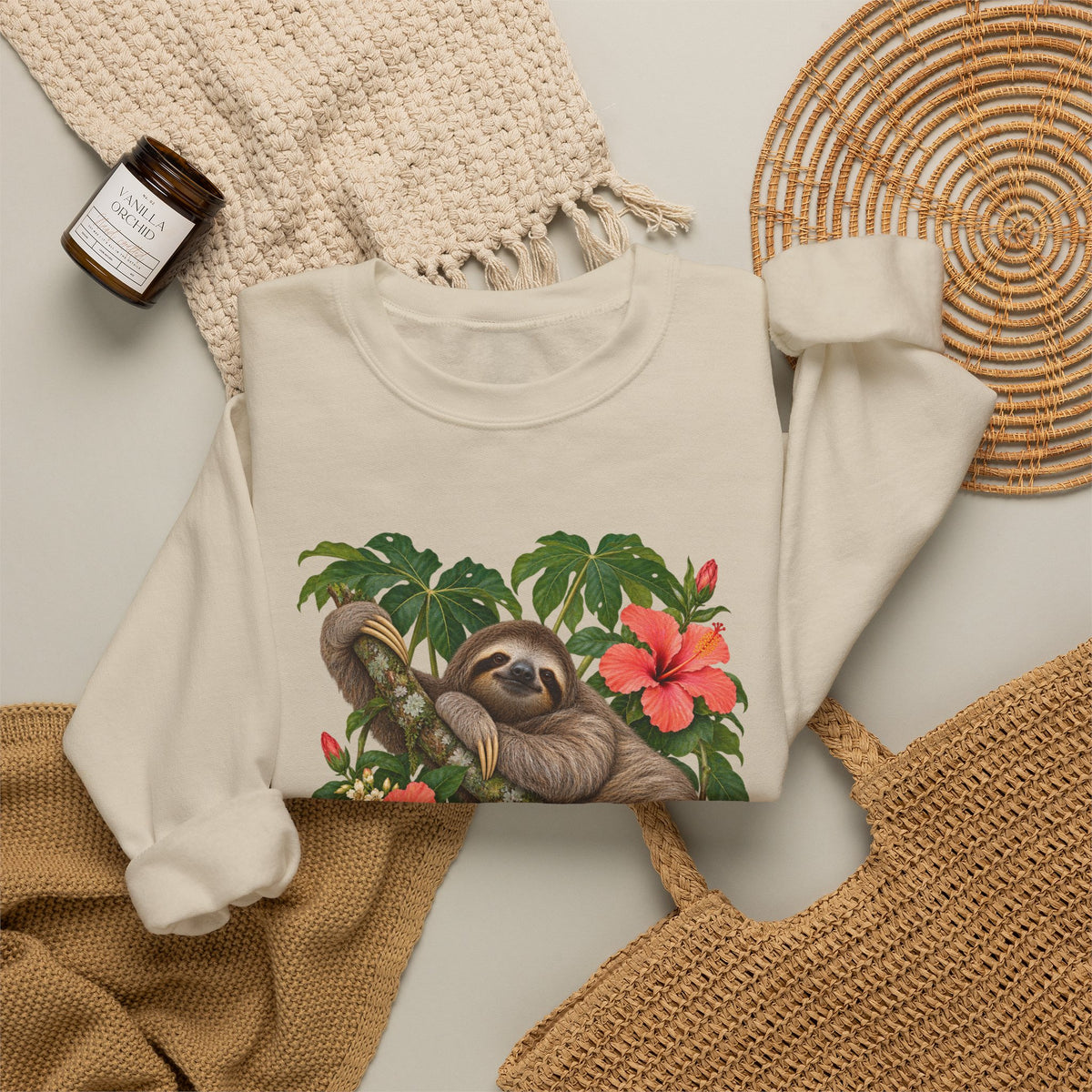 Taking My Sweet Time sweatshirt — a sloth resting on a mossy branch among coral hibiscus, cream blossoms and tropical leaves, on a unisex crewneck