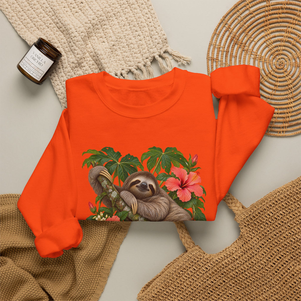 Taking My Sweet Time sweatshirt — a sloth resting on a mossy branch among coral hibiscus, cream blossoms and tropical leaves, on a unisex crewneck