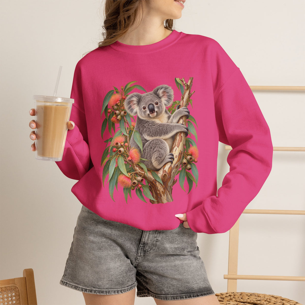 Booked for the Afternoon sweatshirt — a grey koala resting among eucalyptus leaves and coral-pink blossoms, on a unisex crewneck