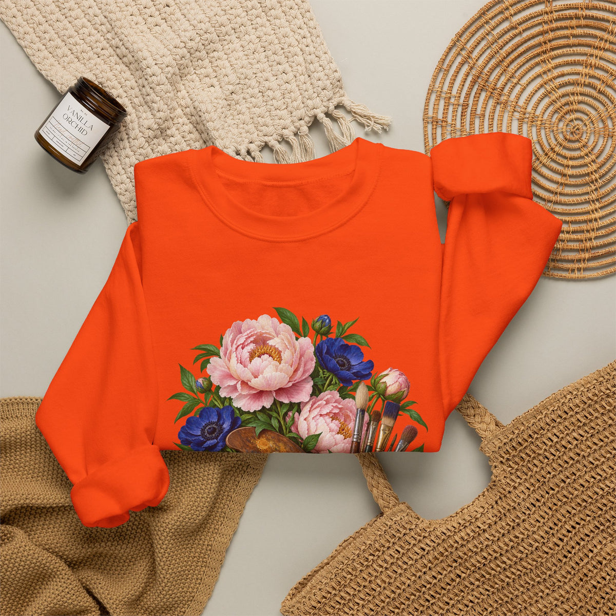 The Colors She Kept crewneck sweatshirt, a paint-covered artist palette beside a cream ceramic jar of brushes with pink peonies and deep blue flowers, image 24 of 28