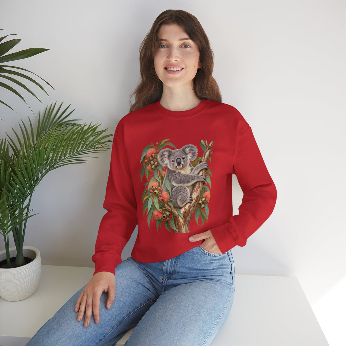 Booked for the Afternoon sweatshirt — a grey koala resting among eucalyptus leaves and coral-pink blossoms, on a unisex crewneck