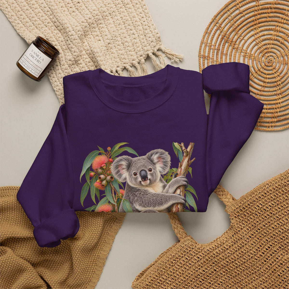 Booked for the Afternoon sweatshirt — a grey koala resting among eucalyptus leaves and coral-pink blossoms, on a unisex crewneck