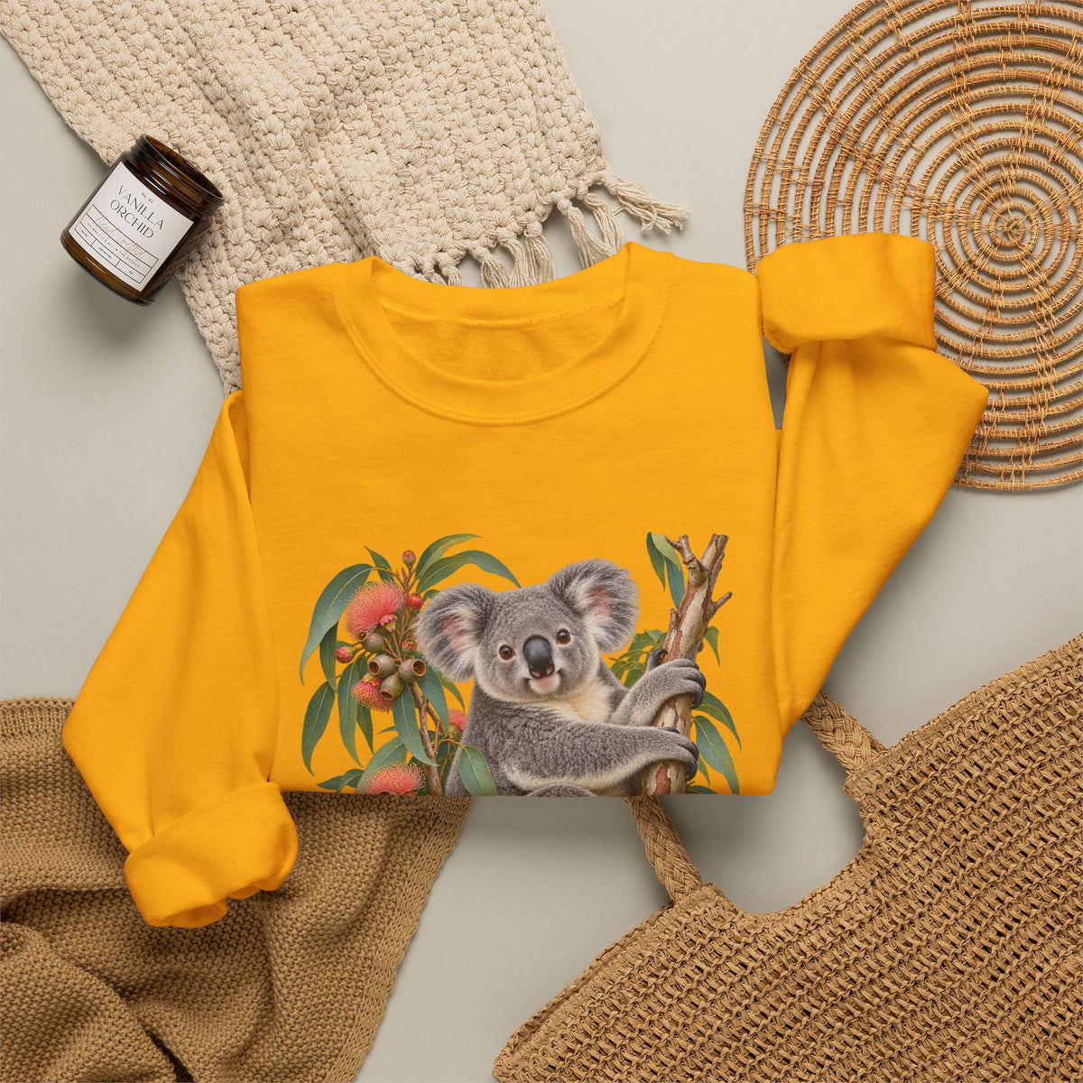Booked for the Afternoon sweatshirt — a grey koala resting among eucalyptus leaves and coral-pink blossoms, on a unisex crewneck