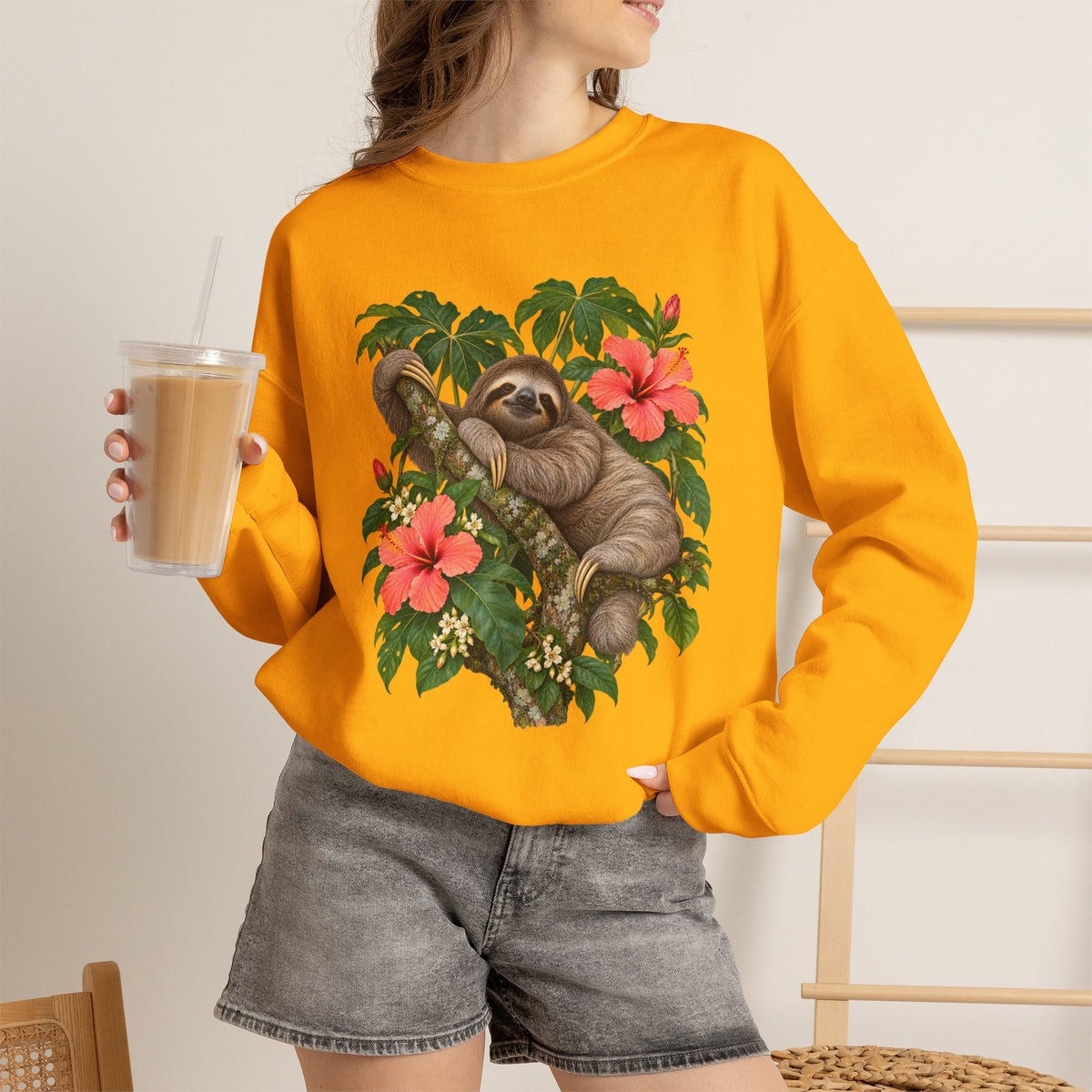 Taking My Sweet Time sweatshirt — a sloth resting on a mossy branch among coral hibiscus, cream blossoms and tropical leaves, on a unisex crewneck