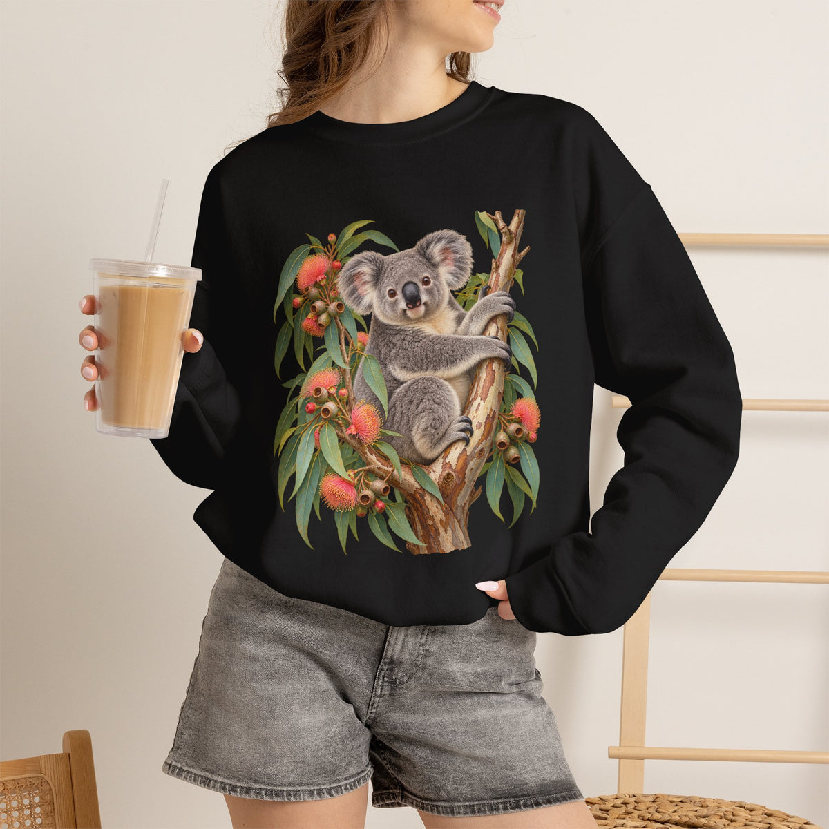 Booked for the Afternoon sweatshirt — a grey koala resting among eucalyptus leaves and coral-pink blossoms, on a unisex crewneck