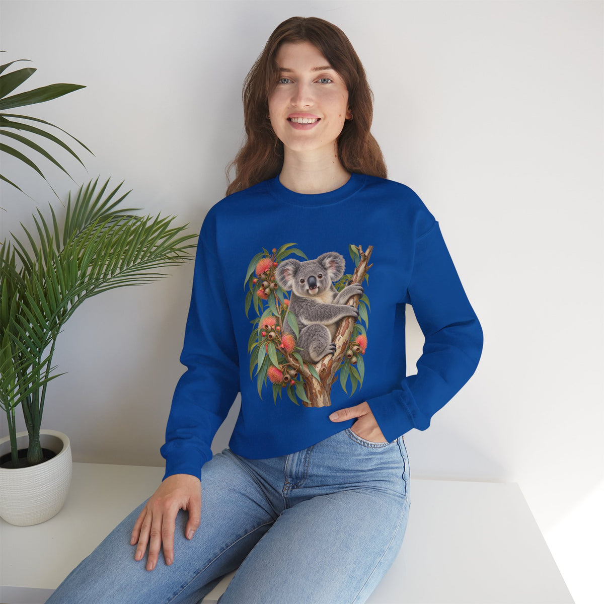 Booked for the Afternoon sweatshirt — a grey koala resting among eucalyptus leaves and coral-pink blossoms, on a unisex crewneck