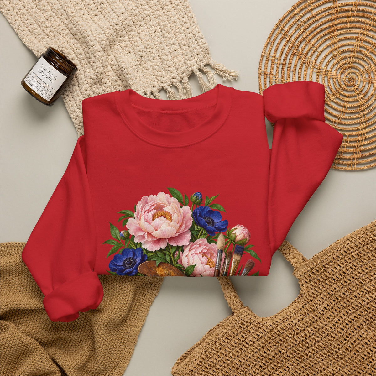 The Colors She Kept crewneck sweatshirt, a paint-covered artist palette beside a cream ceramic jar of brushes with pink peonies and deep blue flowers, image 8 of 28