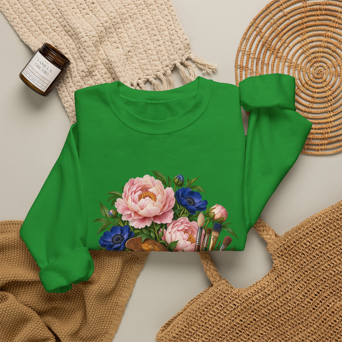 The Colors She Kept crewneck sweatshirt, a paint-covered artist palette beside a cream ceramic jar of brushes with pink peonies and deep blue flowers, image 14 of 28