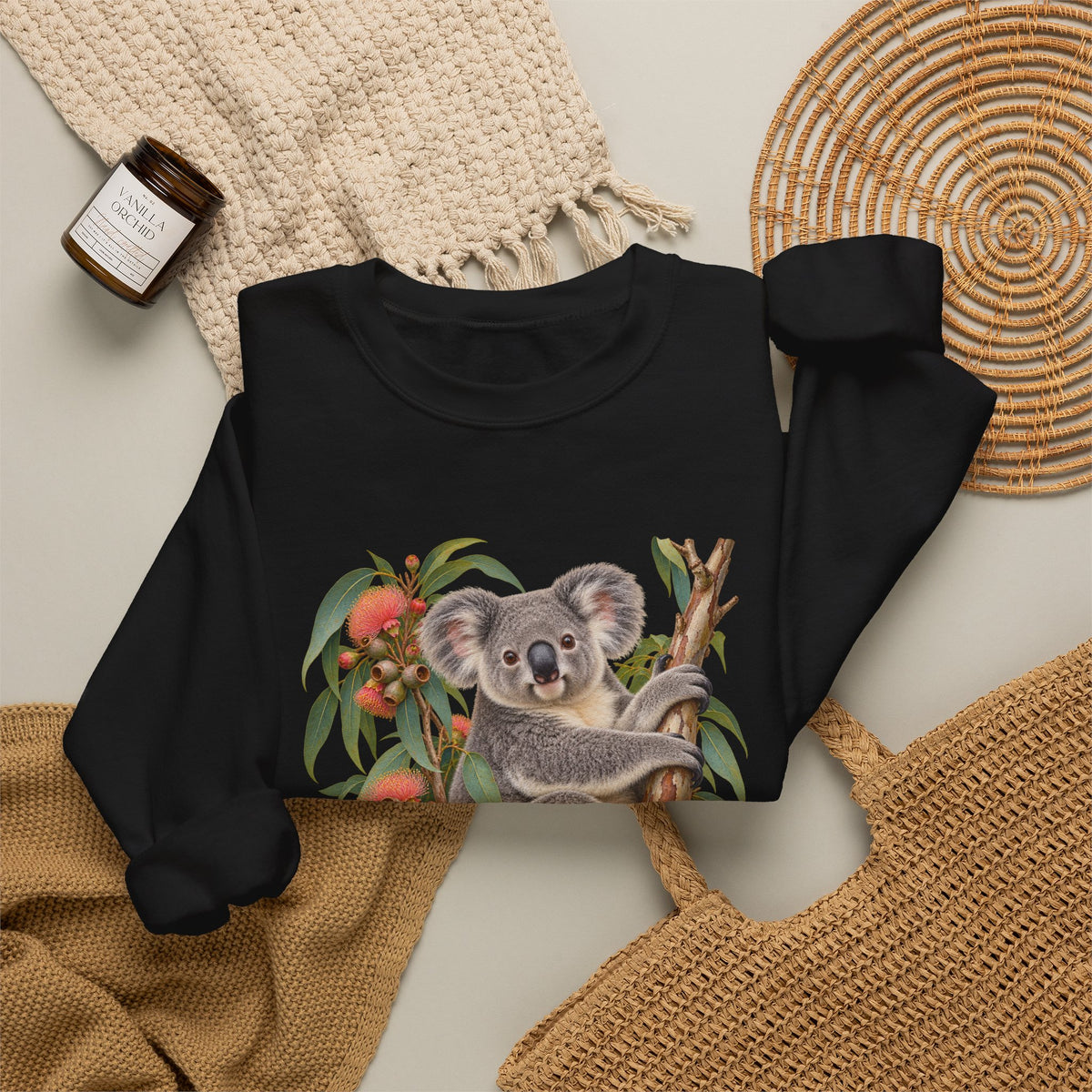 Booked for the Afternoon sweatshirt — a grey koala resting among eucalyptus leaves and coral-pink blossoms, on a unisex crewneck