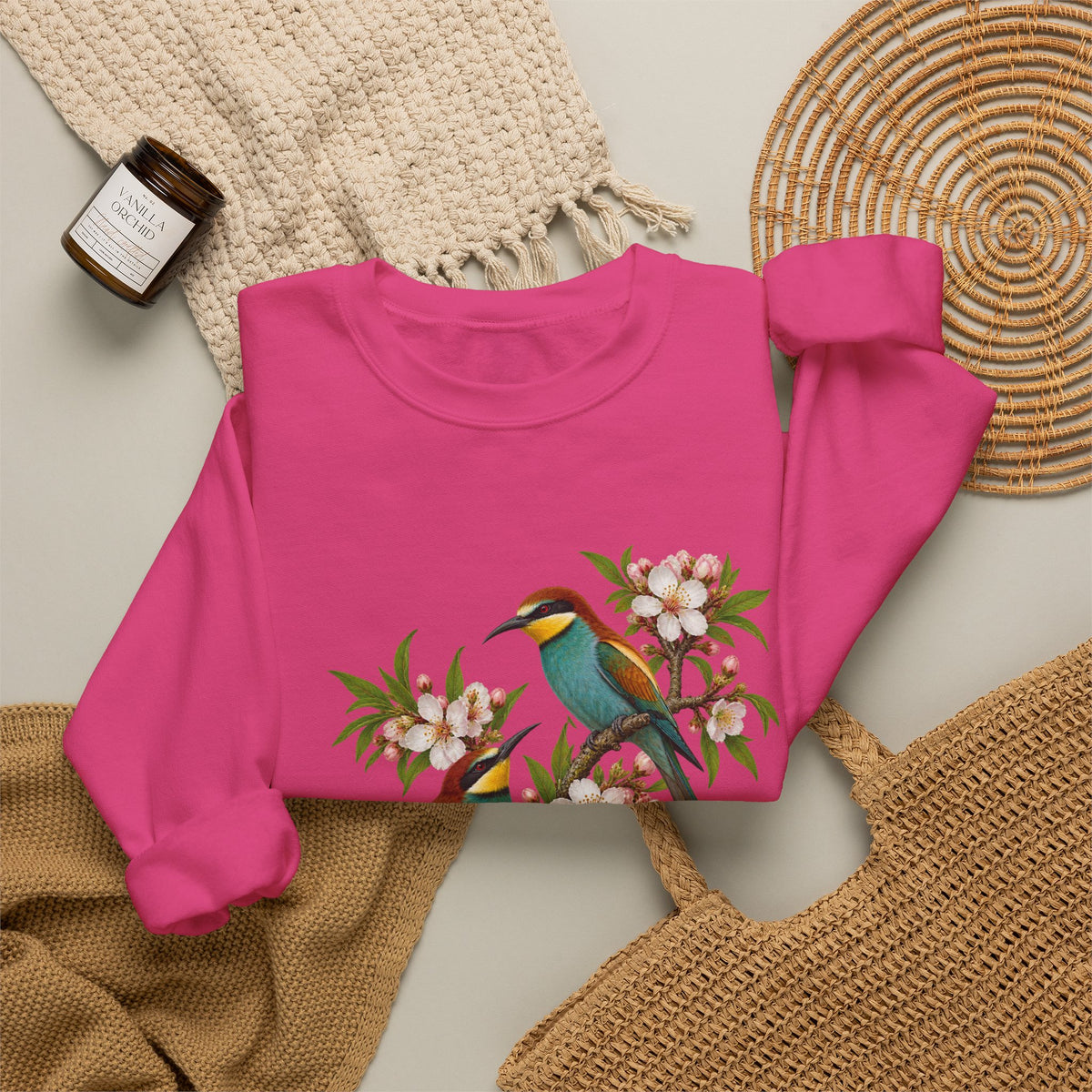 The Scenic Way Home sweatshirt — two birds with teal, golden-yellow and rust plumage perched among cream and blush blossoms, on a unisex crewneck