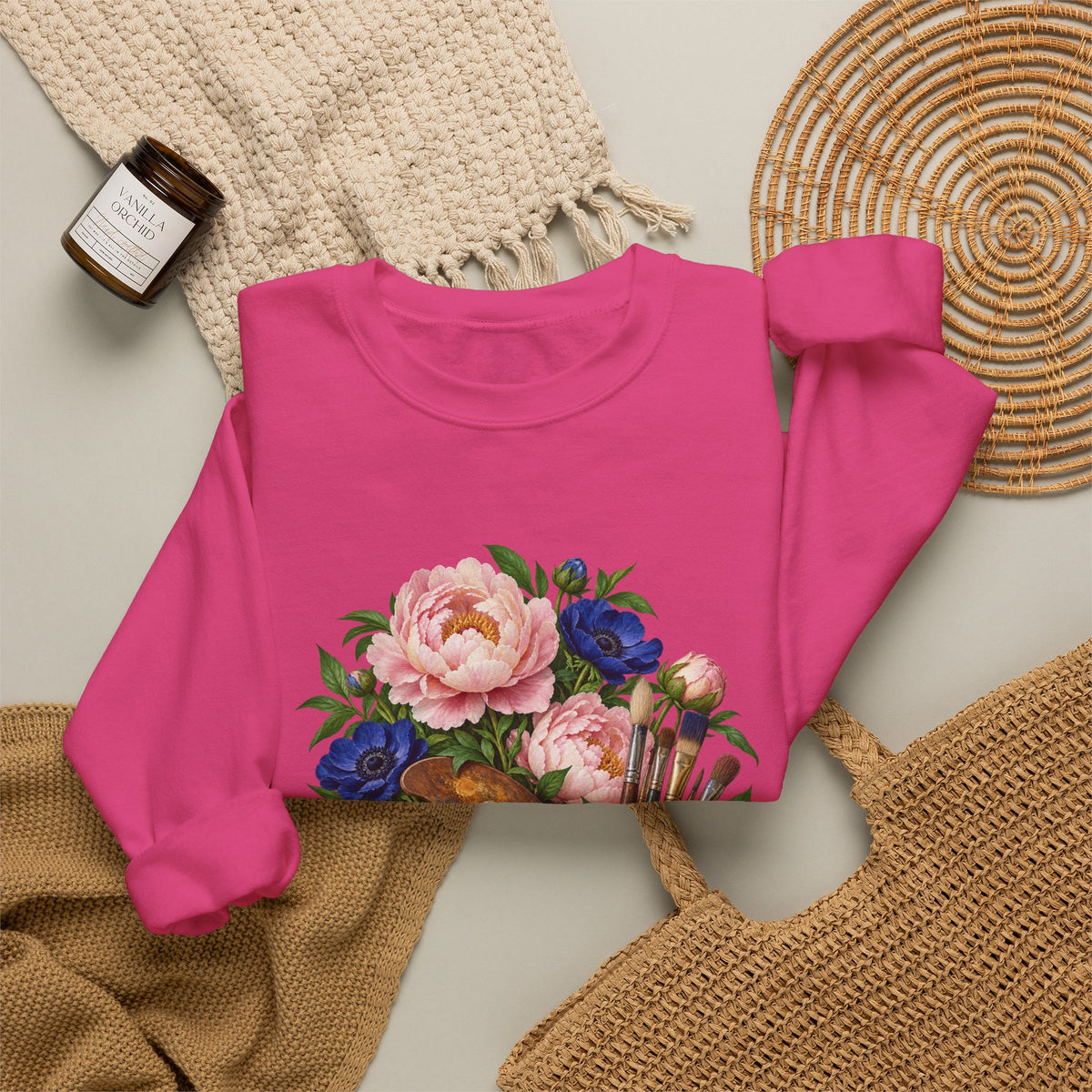 The Colors She Kept crewneck sweatshirt, a paint-covered artist palette beside a cream ceramic jar of brushes with pink peonies and deep blue flowers, image 10 of 28