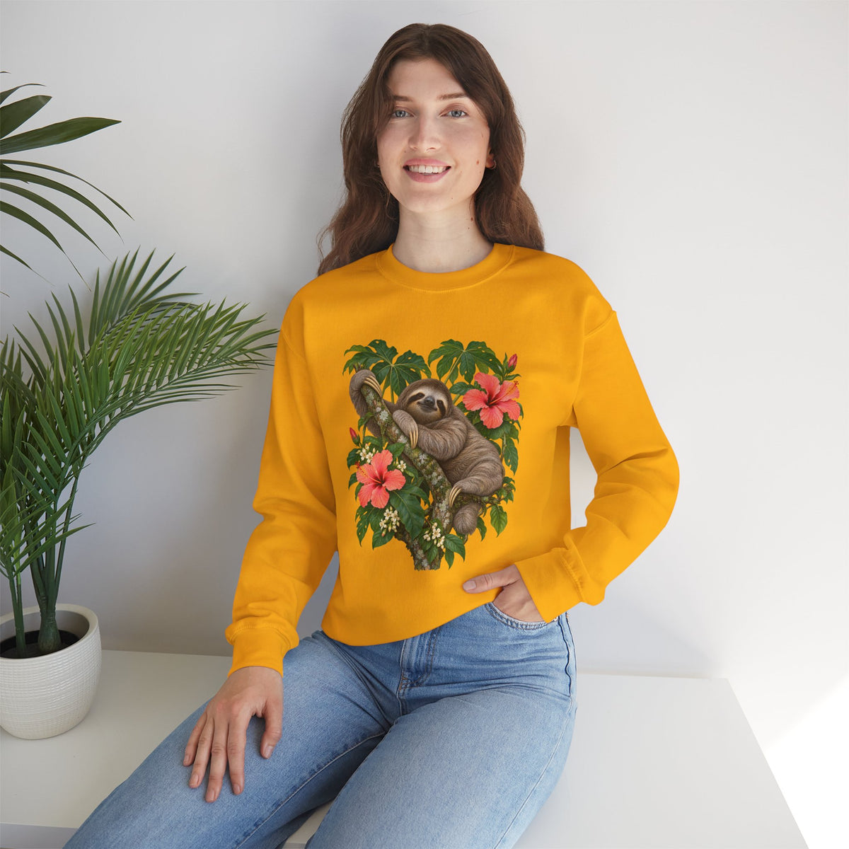 Taking My Sweet Time sweatshirt — a sloth resting on a mossy branch among coral hibiscus, cream blossoms and tropical leaves, on a unisex crewneck