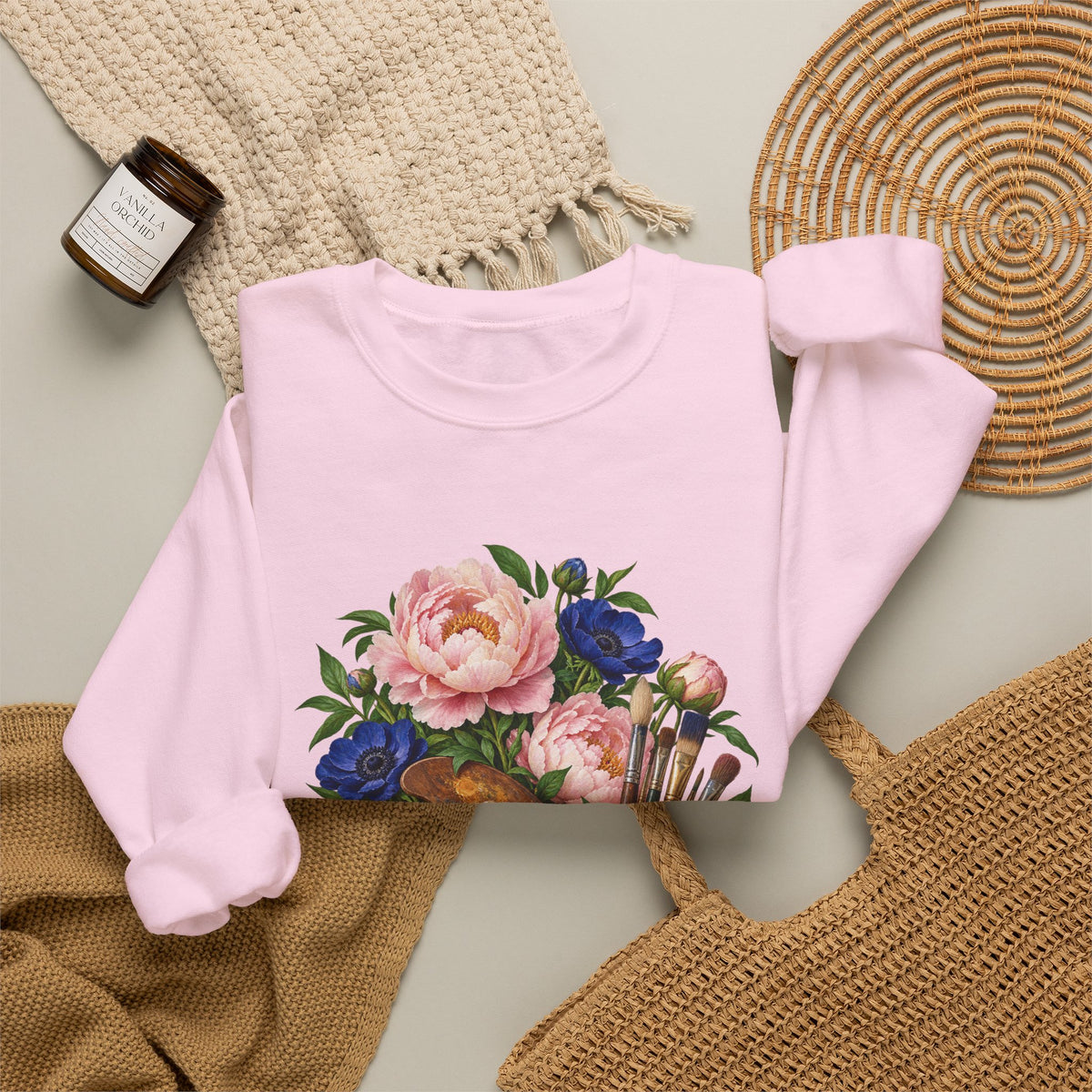 The Colors She Kept crewneck sweatshirt, a paint-covered artist palette beside a cream ceramic jar of brushes with pink peonies and deep blue flowers, image 19 of 28