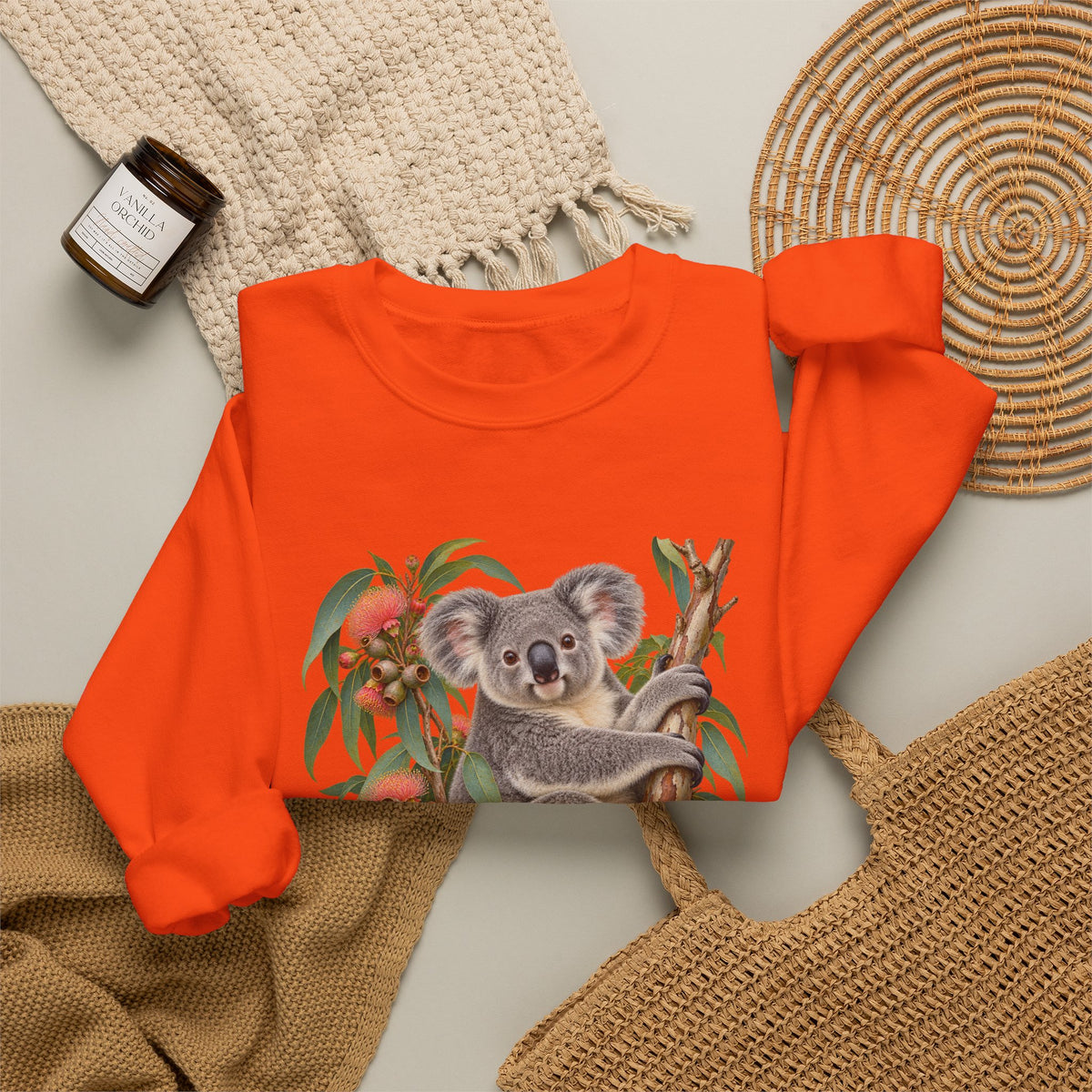 Booked for the Afternoon sweatshirt — a grey koala resting among eucalyptus leaves and coral-pink blossoms, on a unisex crewneck