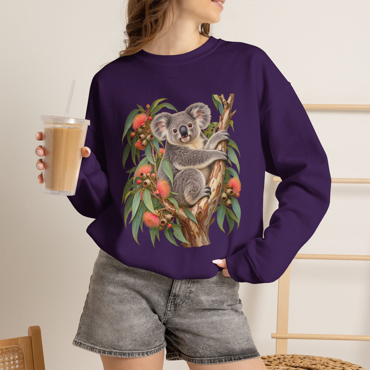 Booked for the Afternoon sweatshirt — a grey koala resting among eucalyptus leaves and coral-pink blossoms, on a unisex crewneck