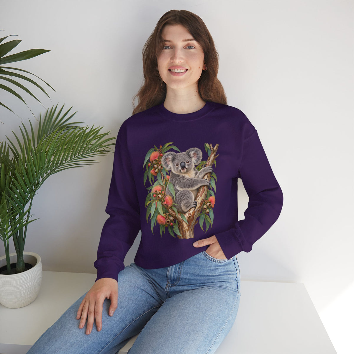 Booked for the Afternoon sweatshirt — a grey koala resting among eucalyptus leaves and coral-pink blossoms, on a unisex crewneck