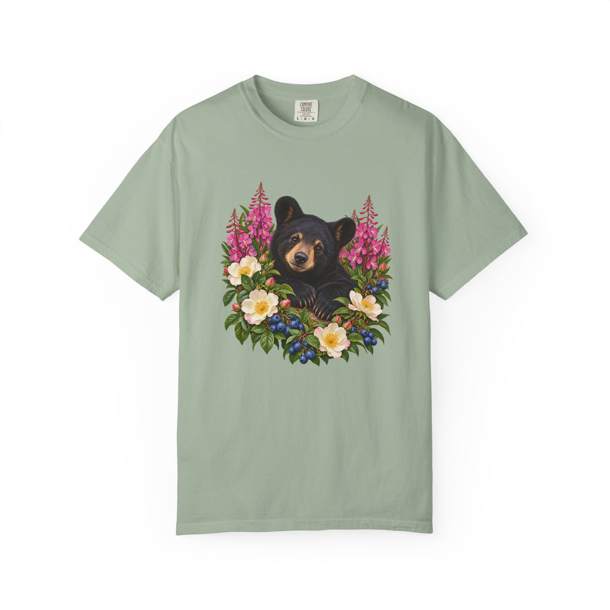 Wildlife botanical tee - a black bear cub standing in a late-summer hillside of fireweed, wild roses and blueberries, no text in the design