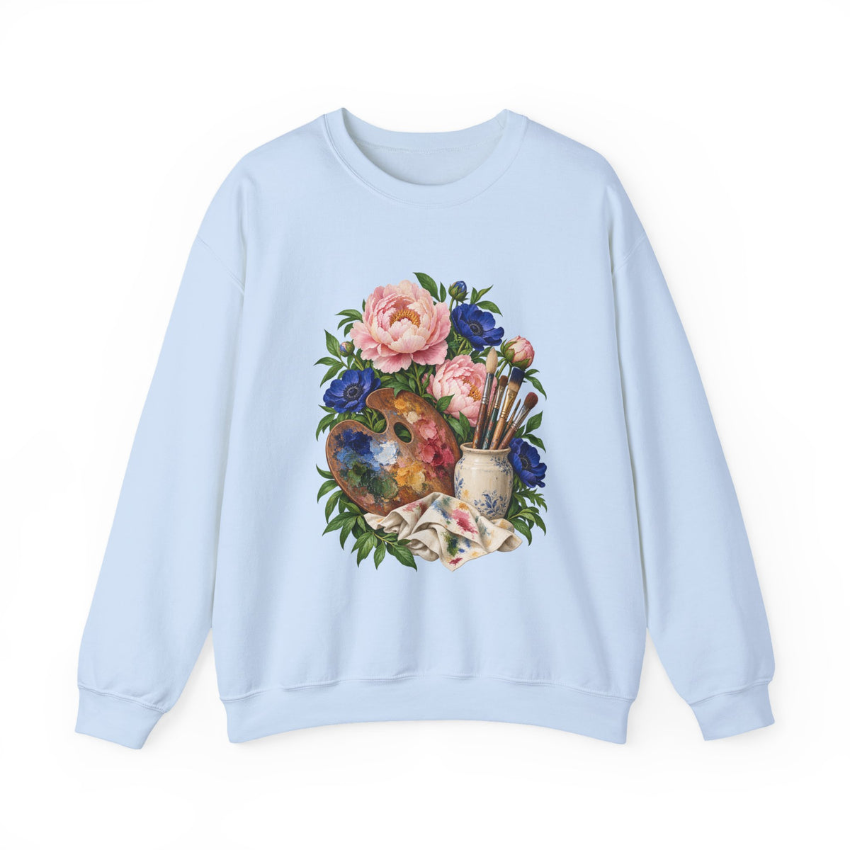 The Colors She Kept crewneck sweatshirt, a paint-covered artist palette beside a cream ceramic jar of brushes with pink peonies and deep blue flowers, image 4 of 28