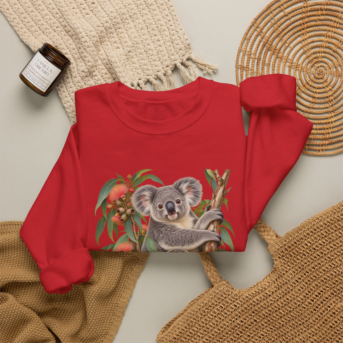 Booked for the Afternoon sweatshirt — a grey koala resting among eucalyptus leaves and coral-pink blossoms, on a unisex crewneck