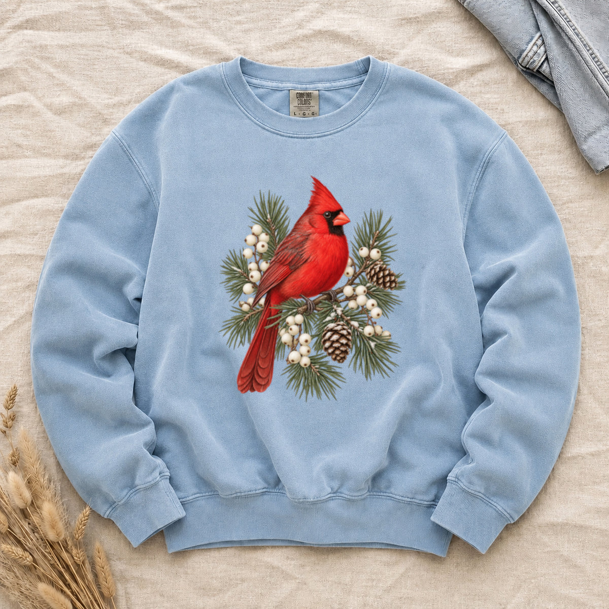 A Flash of Red sweatshirt in Chambray, a red cardinal among evergreen branches, pinecones and white berries
