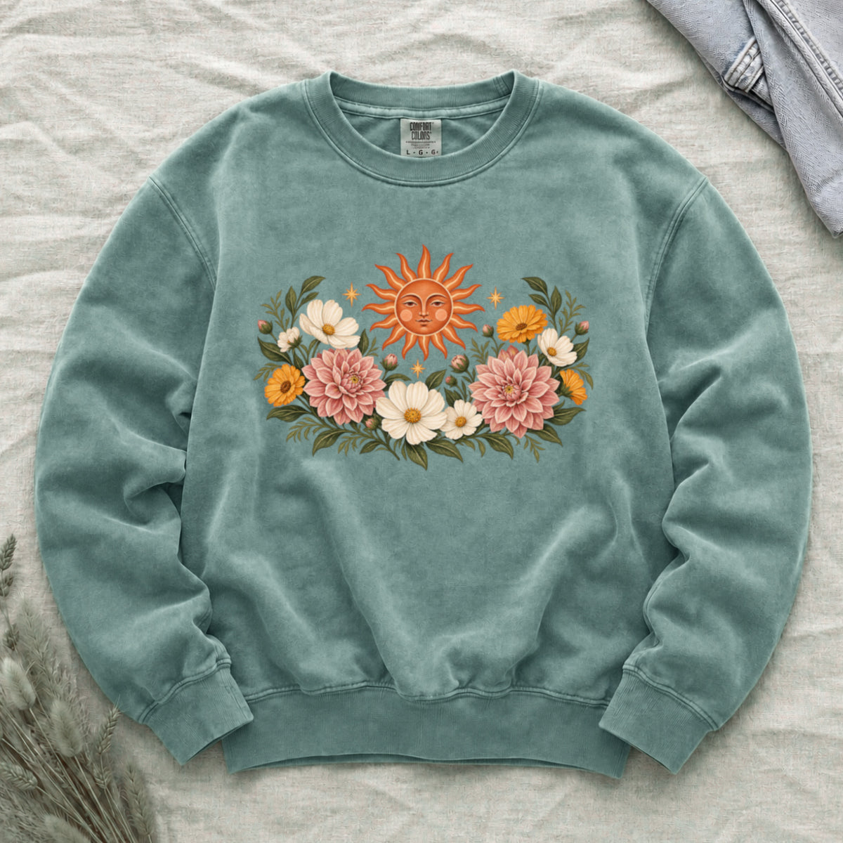A Little Sun to Keep sweatshirt in Light Green, an orange sun rising above pink, cream and golden flowers