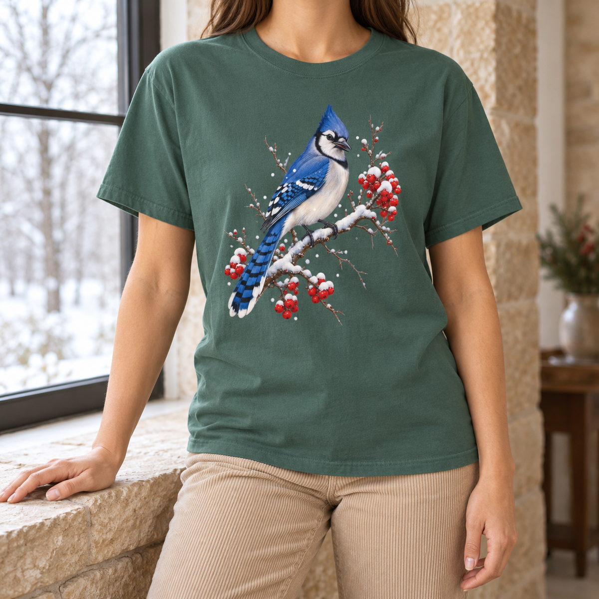 Blue jay winter t-shirt worn by a window – watercolor blue jay bird on a snow-capped winterberry branch with red berries, garment-dyed Comfort Colors cotton tee