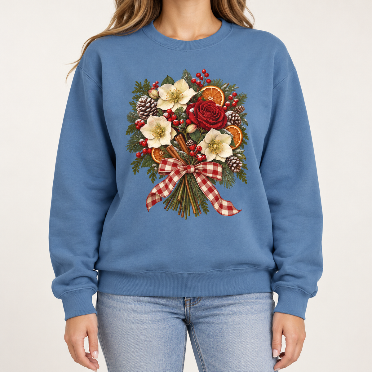 Winter bouquet sweatshirt in Blue Jean – cream hellebores, a red rose, dried orange slices, cinnamon and pinecones tied with a red gingham bow, printed large on the chest of a Comfort Colors crewneck