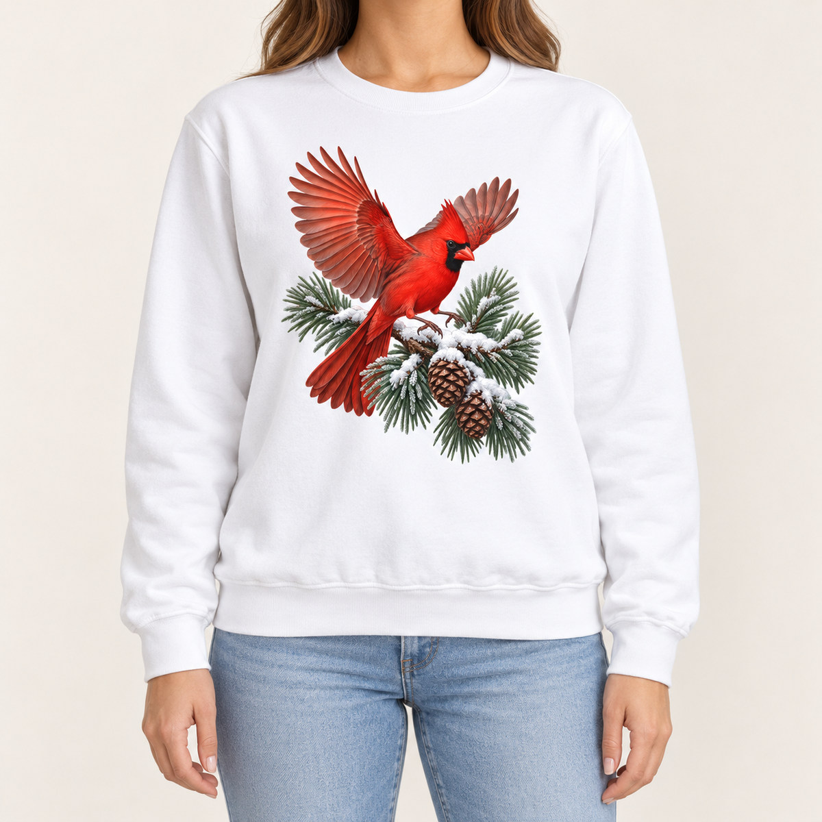 Cardinal in flight sweatshirt in White – a male northern cardinal with wings spread landing on a snow-covered pine bough with pinecones, printed large on the chest of a Comfort Colors crewneck