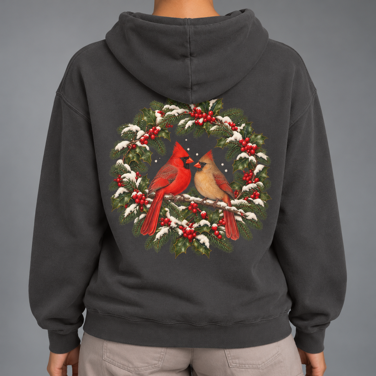 Winter Cardinal hoodie in Pepper worn, close view of the back print with a cardinal pair inside a snowy evergreen and holly wreath