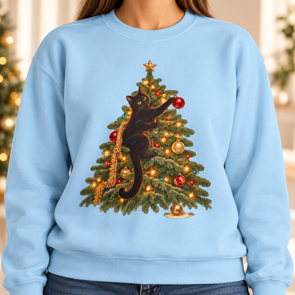 Close-up of the black cat Christmas tree print on the Chambray garment-dyed crewneck sweatshirt – cat reaching for a red ornament, gold star, lights