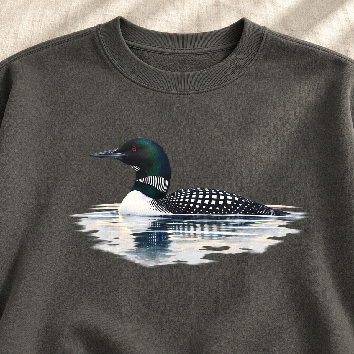 Common Loon Sweatshirt in Pepper, flat lay - watercolor loon on misty water on a charcoal garment-dyed Comfort Colors crewneck