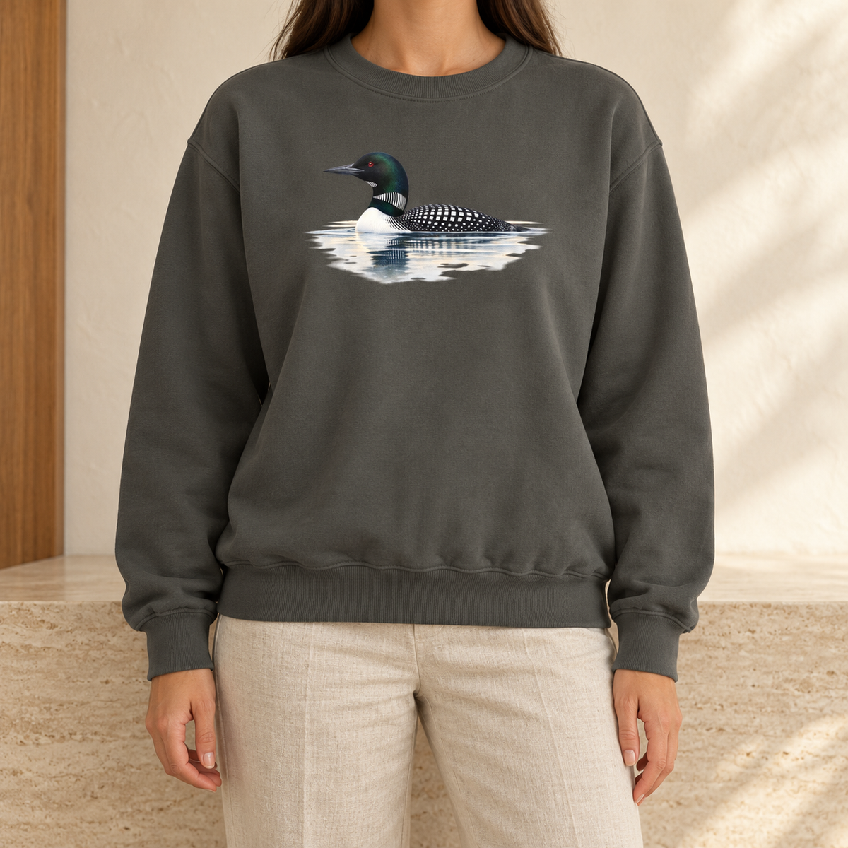 Common Loon Sweatshirt in Pepper - watercolor loon on a misty lake printed on a charcoal garment-dyed Comfort Colors crewneck, worn by a woman