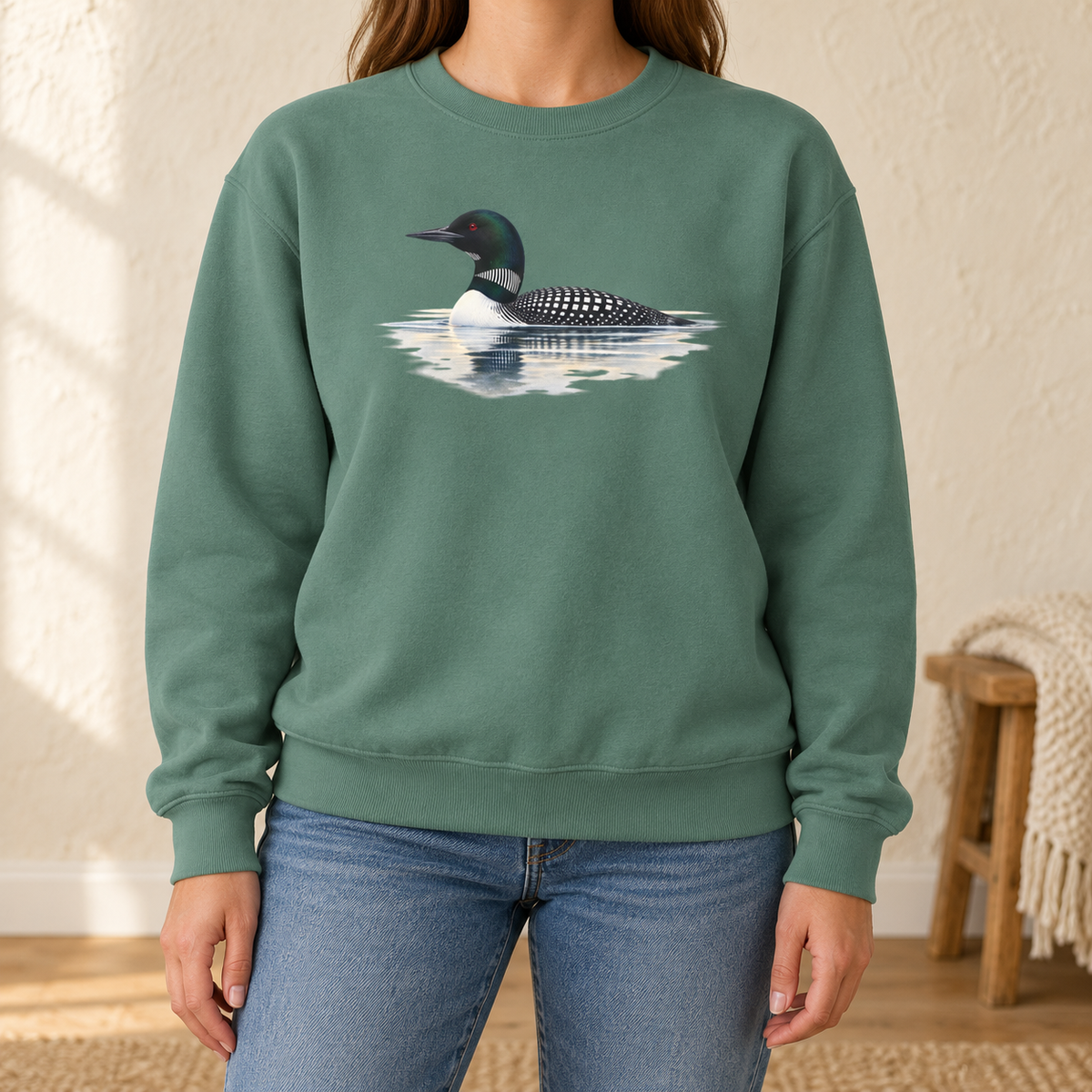 Common Loon Sweatshirt in Light Green - watercolor loon on still water printed on a washed sage Comfort Colors crewneck, worn by a woman