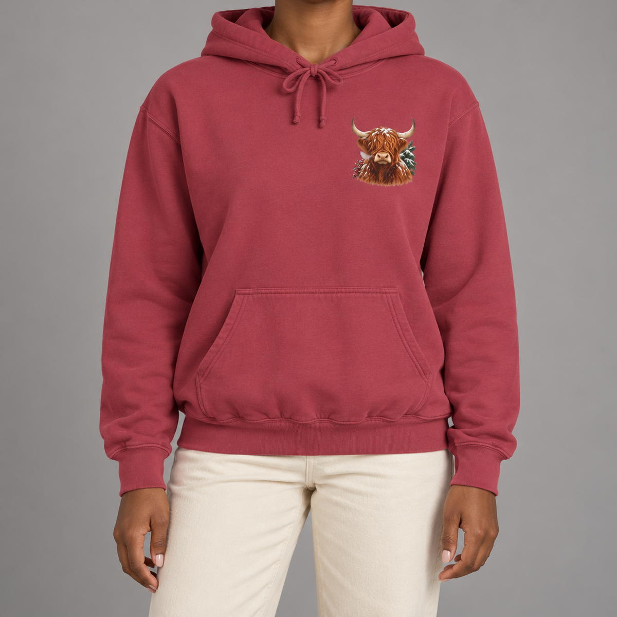 Winter Highland Cow hoodie in Crimson worn, close view of the small snowy highland cow crest on the left chest