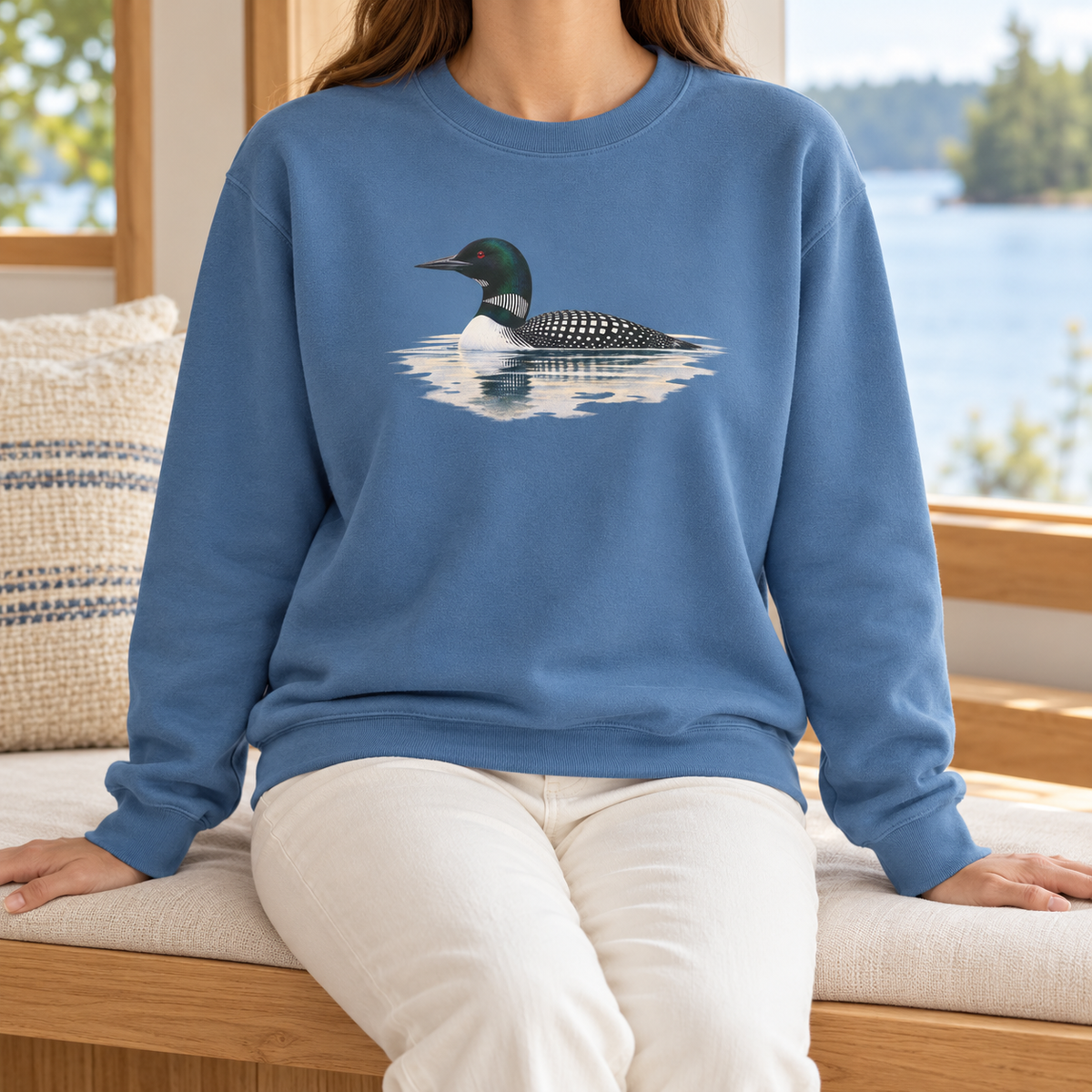 Common Loon Sweatshirt in Blue Jean - watercolor loon on still water printed on a washed denim-blue Comfort Colors crewneck, seated on an oak bench