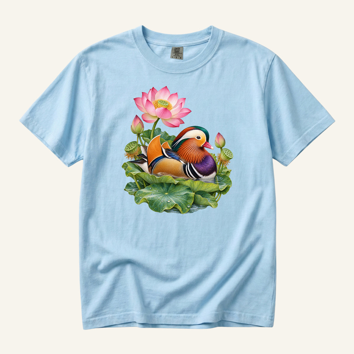 Mandarin duck with orange sail feathers and a purple breast among pink lotus blossoms and green leaves, printed on a Chambray blue Comfort Colors 1717 unisex t-shirt