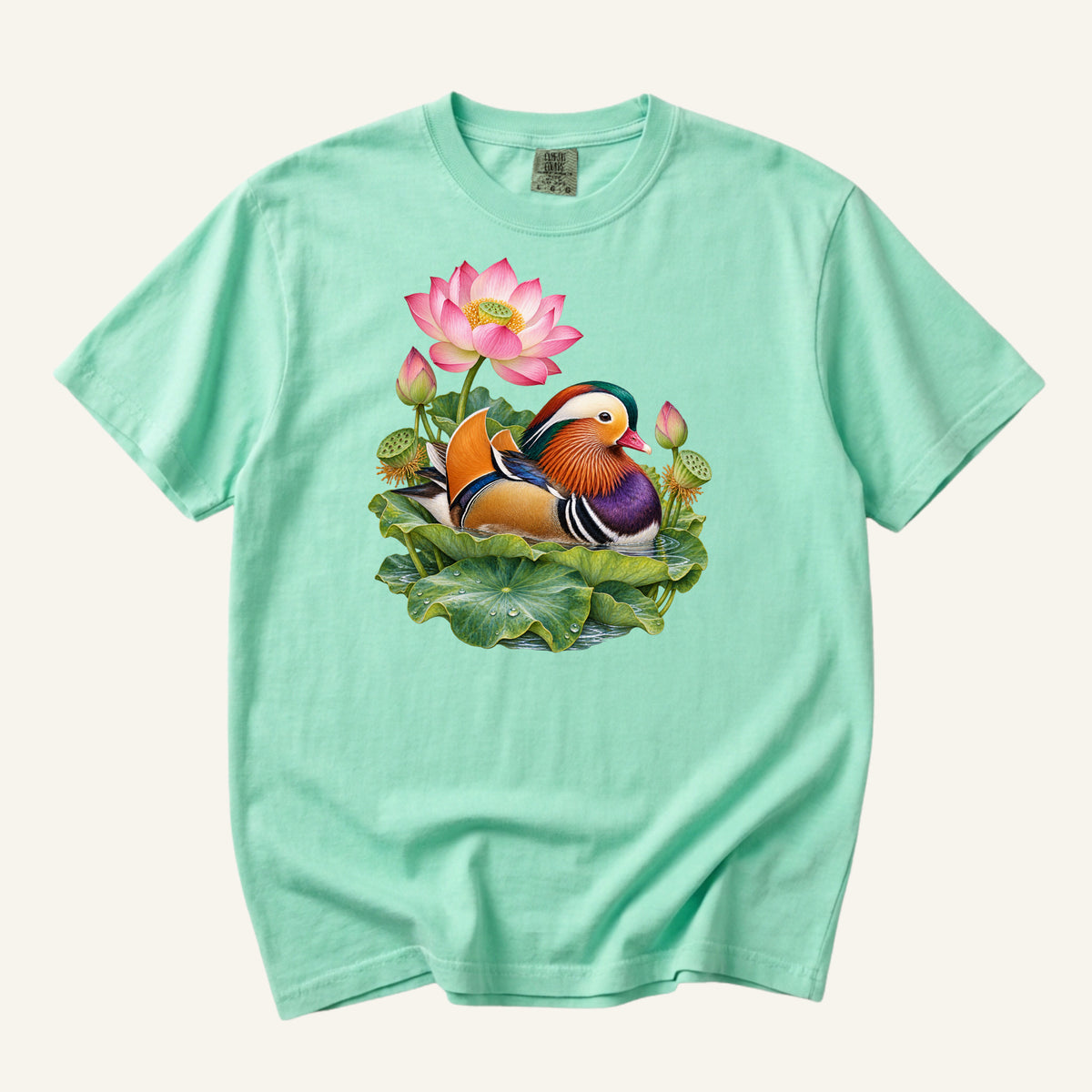 Mandarin duck with orange sail feathers and a purple breast among pink lotus blossoms and green leaves, printed on an Island Reef aqua Comfort Colors 1717 unisex t-shirt