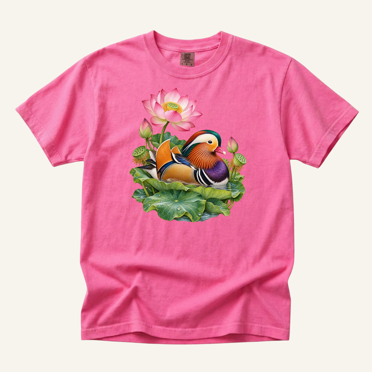 Mandarin duck with orange sail feathers and a purple breast among pink lotus blossoms and green leaves, printed on a Neon Pink Comfort Colors 1717 unisex t-shirt