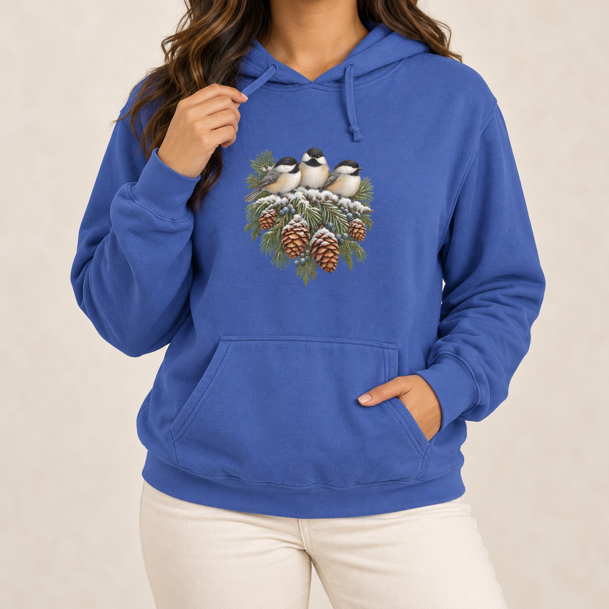 Winter Chickadee hoodie in Flo Blue worn, front view with three chickadees on a snowy spruce bough