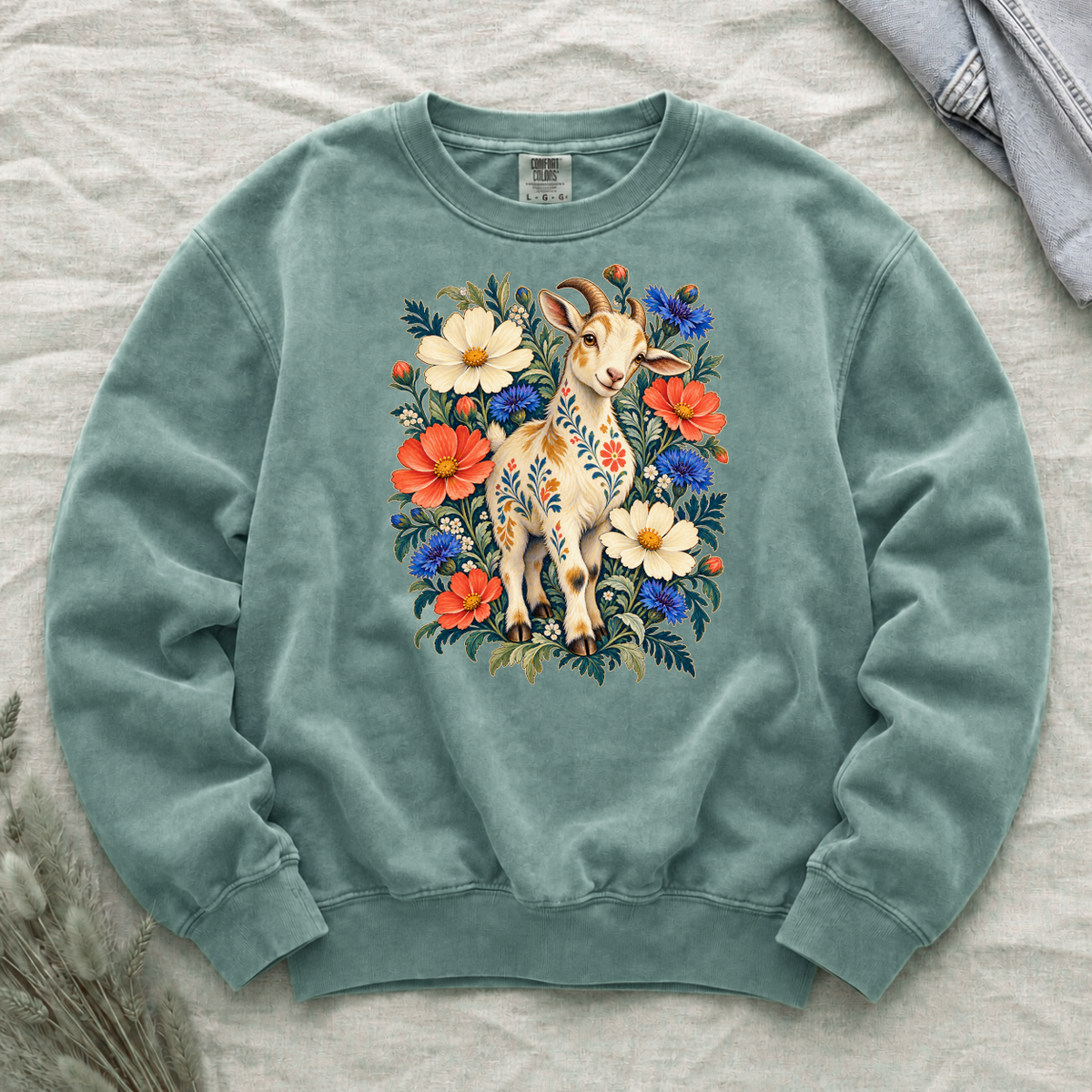 Folk-art goat patterned with flowers among coral and blue blooms on a Light Green Comfort Colors crewneck sweatshirt