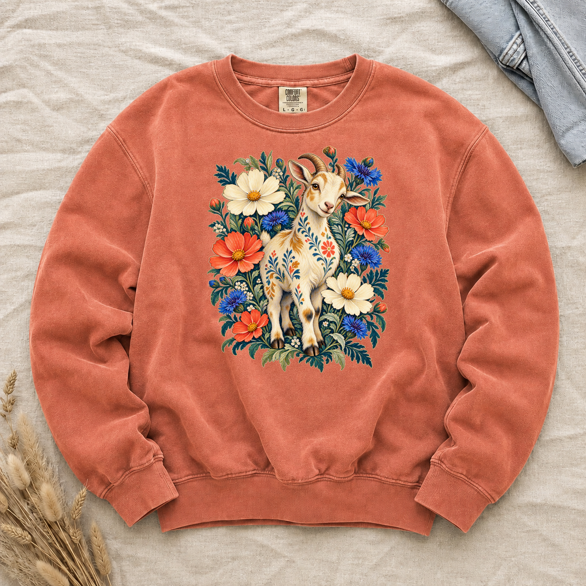 Folk-art goat patterned with flowers among coral and blue blooms on a Terracotta Comfort Colors crewneck sweatshirt