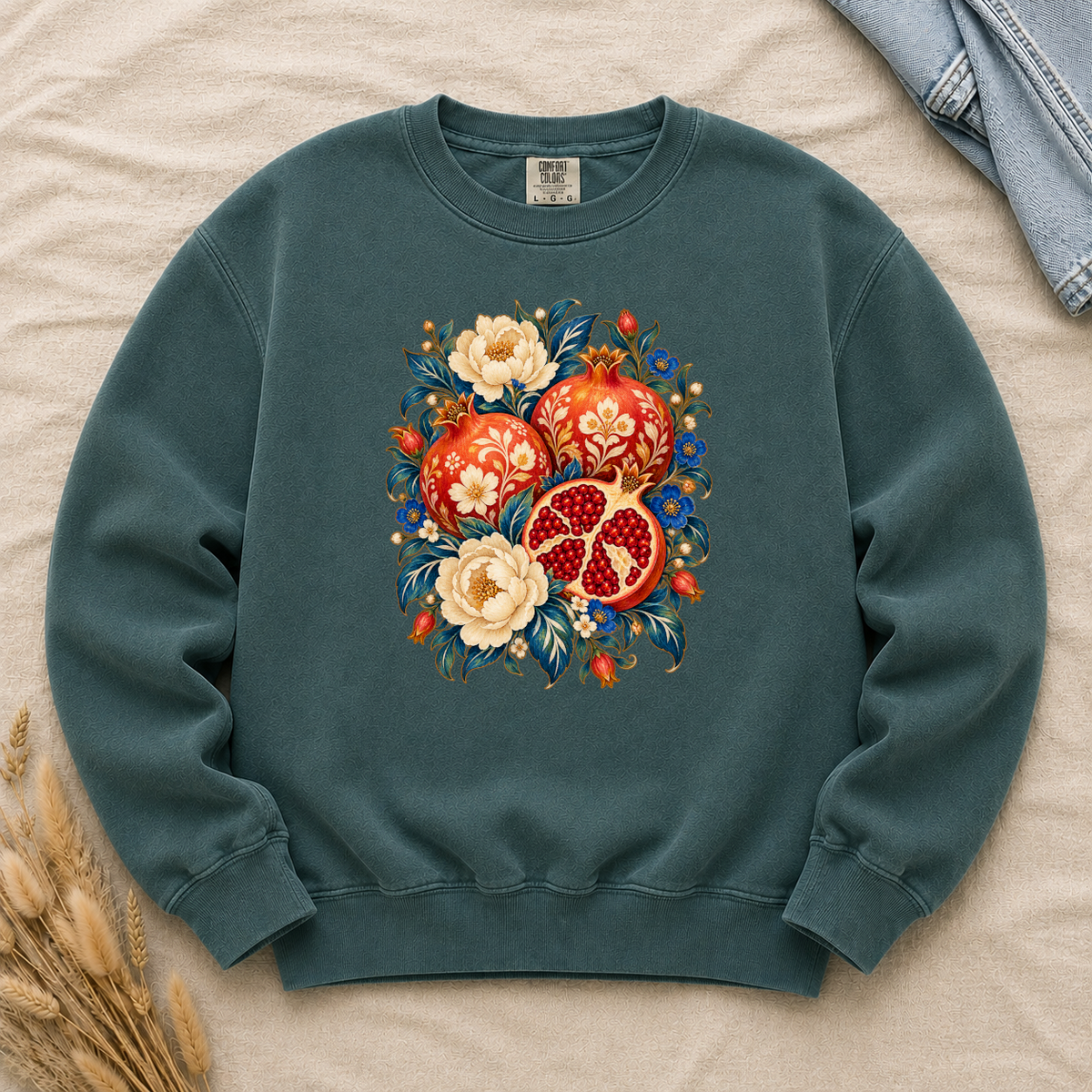 Folk-art pomegranates and cream blossoms printed on a Blue Spruce dark green Comfort Colors crewneck sweatshirt