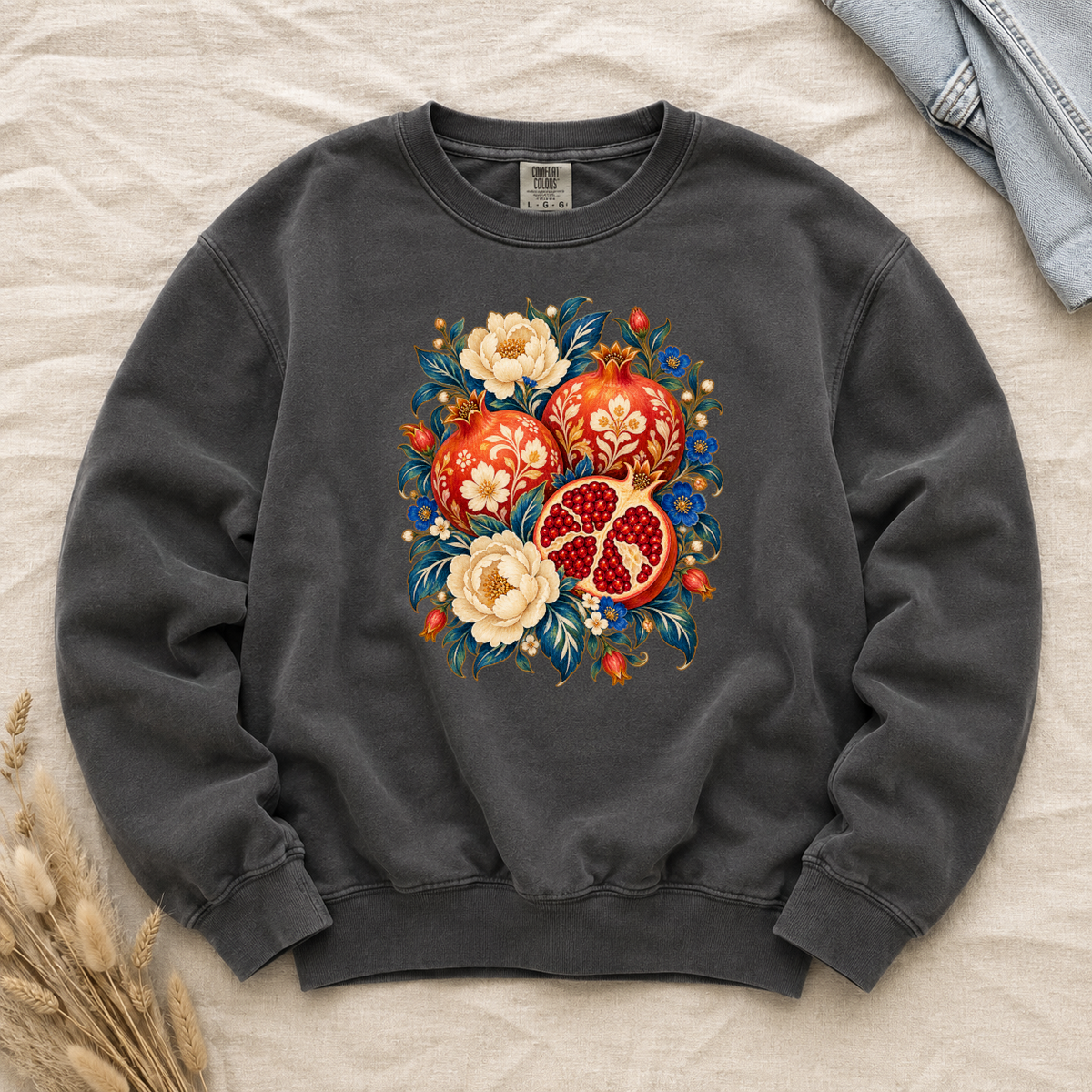 Folk-art pomegranates and cream blossoms printed on a Pepper charcoal Comfort Colors crewneck sweatshirt