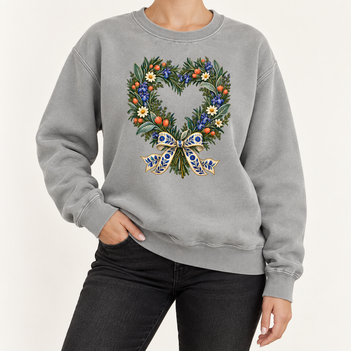 Heart-shaped floral wreath with a blue bow, printed large on the front of the sweatshirt