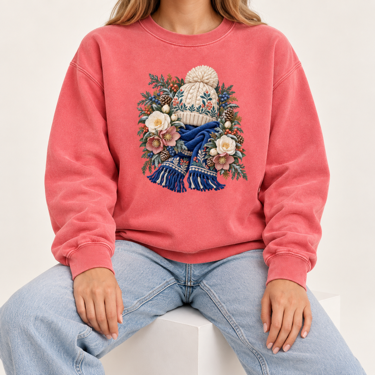 Floral knit hat and scarf sweatshirt, relaxed unisex fit, adult sizes S to 3XL — a cream pom-pom hat above a deep blue fringed scarf, framed by evergreen, pinecones and cream roses
